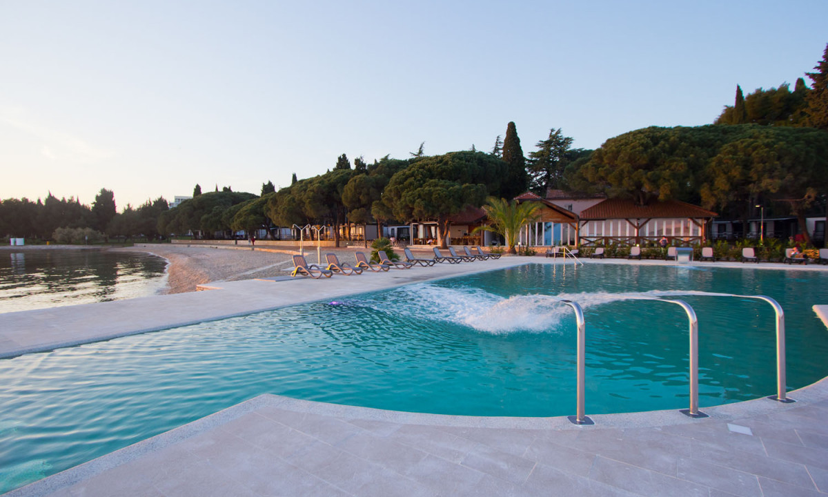 Swimming pool with lounge chairs and trees surrounding it, situated near a serene beach at Boutique Camp Materada Beach