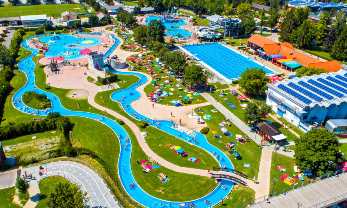 Lazy river winding through a bustling water park, surrounded by sunbathers and lush greenery at Terme Catez