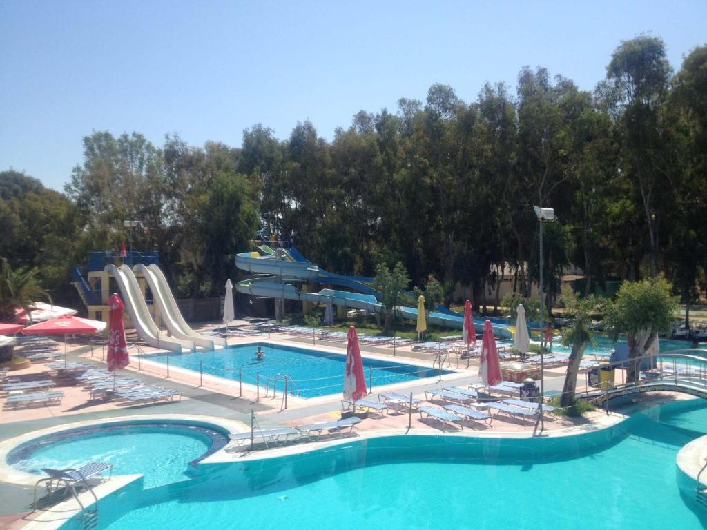 Waterslides curve into a pool surrounded by lounge chairs and umbrellas, amidst trees at Golden Sunset