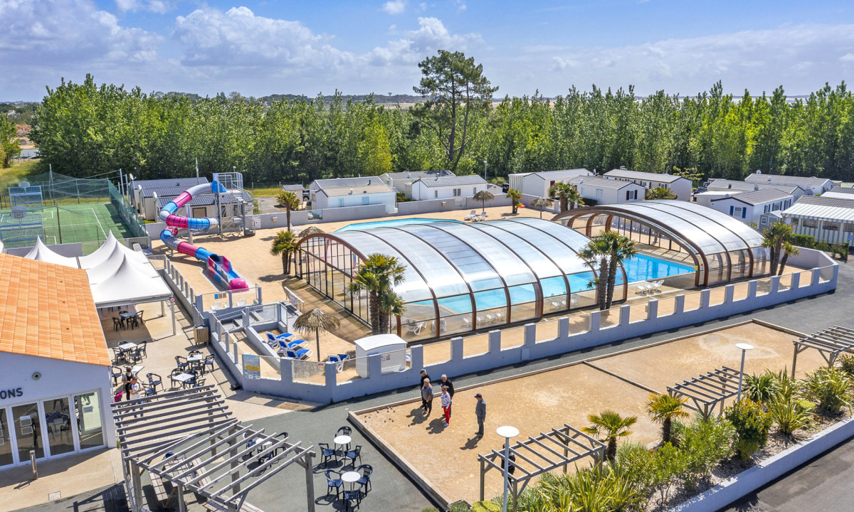 Covered swimming pools adjacent to playground and slides, amidst mobile homes and greenery at Les Rouilleres