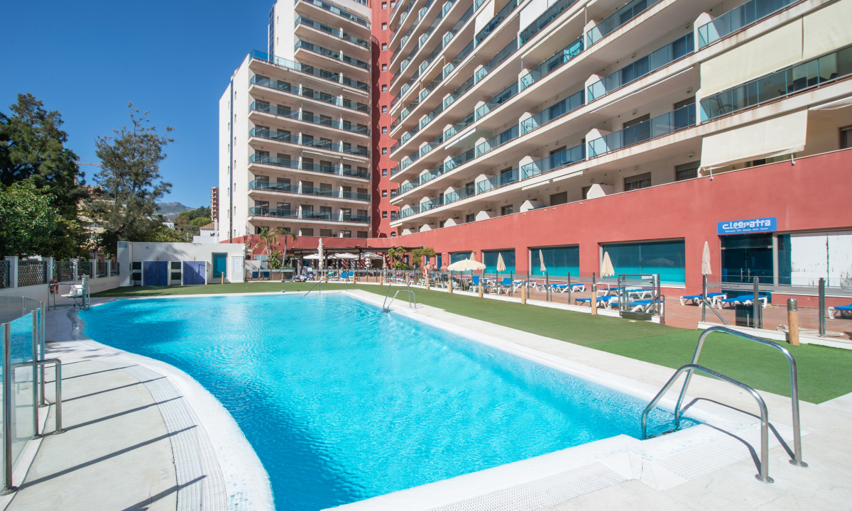 Swimming pool glistening under the sun, surrounded by sun loungers and tall hotel buildings; perfect relaxation spot at Benalmádena Príncipe