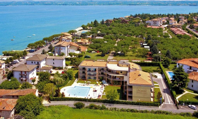 Buildings and swimming pool near greenery by the lakeside, surrounded by residential houses and trees at Residence Nettuno
