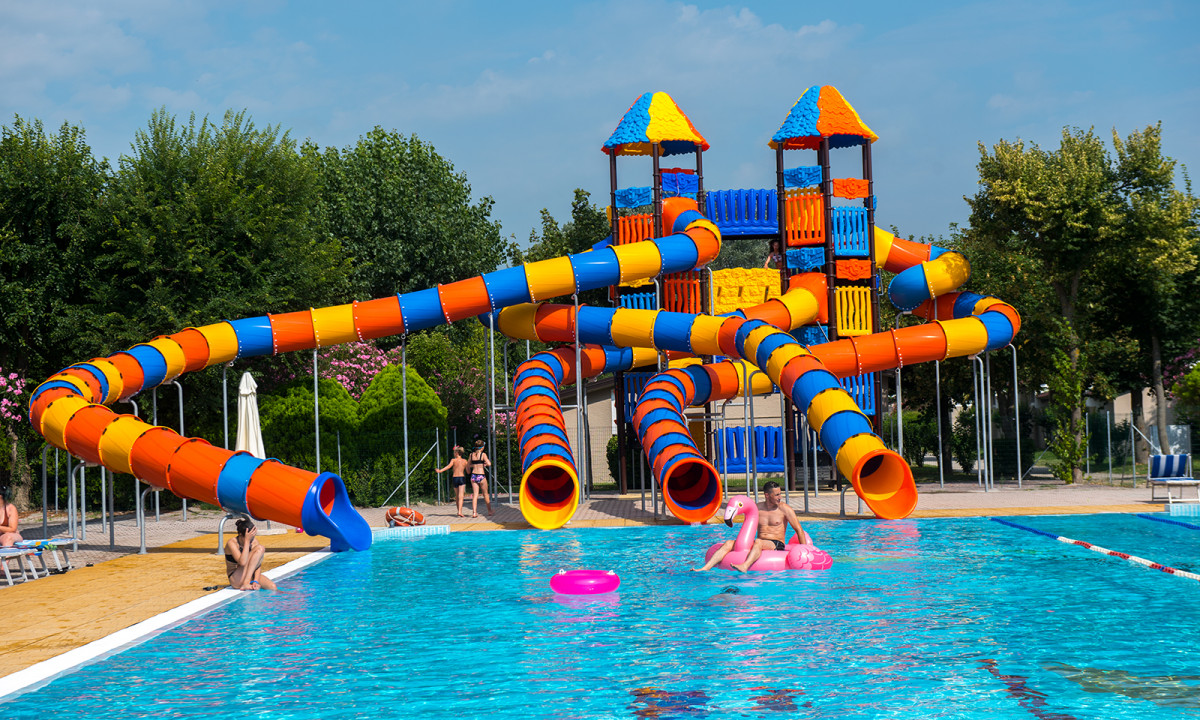 Colorful, twisting water slides tower above swimmers enjoying a large, clear pool at San Francesco