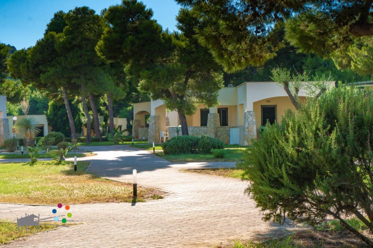 Bungalows with stone pillars beneath pine trees and surrounded by lush greenery at Spiaggia Lunga